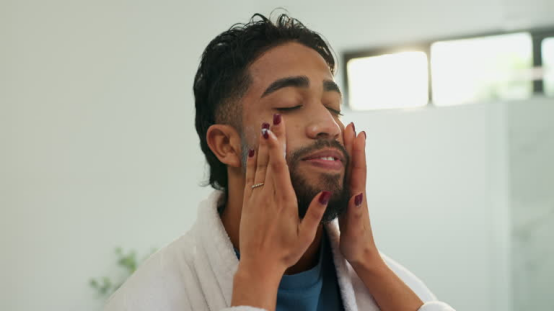Man in a bathrobe cleans his face, preparing to use a nose hair trimmer afterward