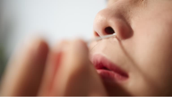 Close-up of a person using a cotton swab near the nose (this method is distinct from the nose hair trimmer, the focus of the FAQ guide)